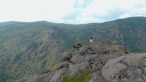 Luchtfoto, Drone vliegen over de zittende meisje op een rotswand — Stockvideo