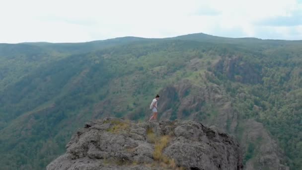 Беспилотник пролетает над впечатляющими горами с девушкой на скале, эффект головокружения — стоковое видео