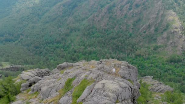 Дрон літає над вражаючими горами з дівчиною, що йде по скелі — стокове відео