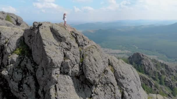 Una giovane donna è in piedi sul bordo di una scogliera di montagna impressionante, dolly zoom — Video Stock