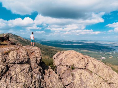 Adam bir dağ uçurumun üzerinde duruyor ve mesafe içine görünüyor. şaşırtıcı görünümü