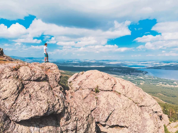 Adam bir dağ uçurumun üzerinde duruyor ve mesafe içine görünüyor. şaşırtıcı görünümü