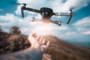 Erkek el günbatımı üzerinde alıcı dron. Güvenli dört helikopter pilotlar Palm'da açılış