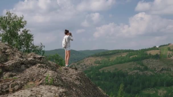 Vrouw fotograaf maakt een foto van een berglandschap op de camera — Stockvideo