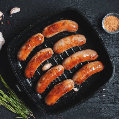 Üzerinde siyah bir taş tablo üzerinde siyah bir tavada kızarmış sosis üstten görünüm