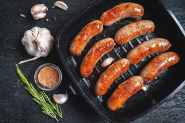 Üzerinde siyah bir taş tablo üzerinde siyah bir tavada kızarmış sosis üstten görünüm