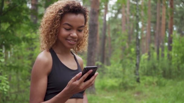 Czarny, młoda kobieta, za pomocą smartfona po joggingu i pokazuje zielony ekran, aby aparat w zwolnionym tempie — Wideo stockowe