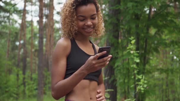 Jeune femme noire utilisant un smartphone après le jogging et montre l'écran vert à la caméra au ralenti — Video