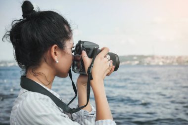 Woman photographer, taking pictures of landscape at sea clipart