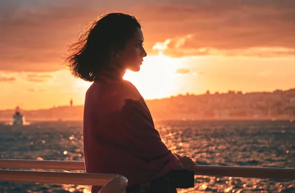 Schöne Frau, die auf Deck des Kreuzfahrtschiffes steht und dem Sonnenuntergang zusieht. — Stockfoto