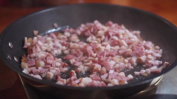 Bacon picado são fritos em uma frigideira quente. zoom em — Vídeo de Stock