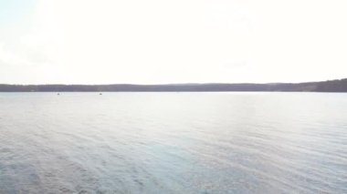 Geri ormandaki ağaçların arasından gölde tekne üzerinde uçan