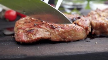 ahşap bir masa üzerinde sulu ızgara biftek kesilmiş eller