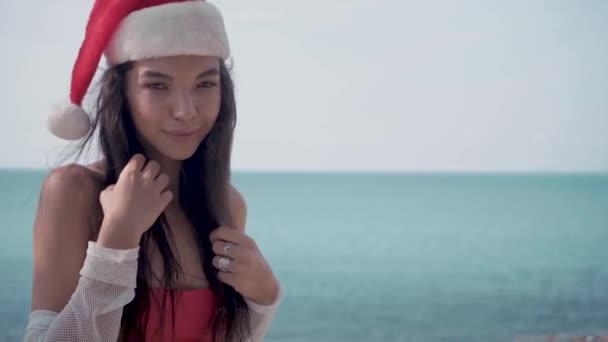 Молодая сексуальная женщина у бассейна в шляпе Санта-Клауса празднует Новый год и Рождество — стоковое видео