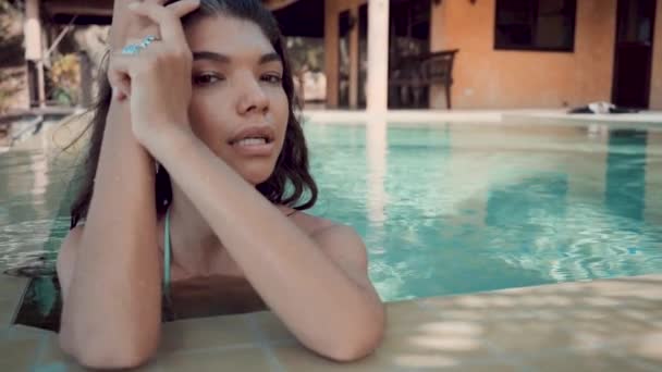 Jeune femme glamour en bikini debout au bord de la piscine sur la villa et regardant la caméra — Video