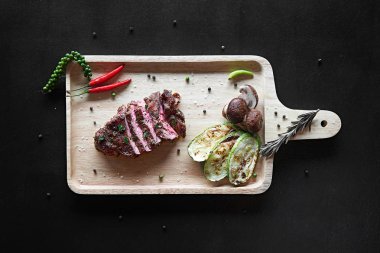 Baharatlar ve sebze kesme tahtası üzerinde ızgara sığır eti biftek. Üstten görünüm