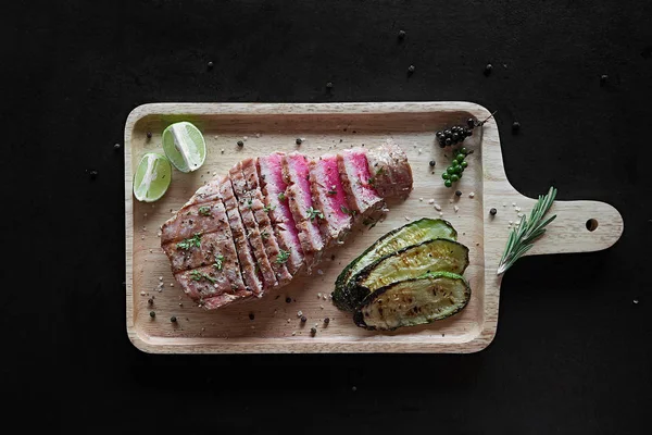 Baharatlar ve sebze kesme tahtası üzerinde ızgara orkinos biftek. Üstten görünüm — Stok fotoğraf
