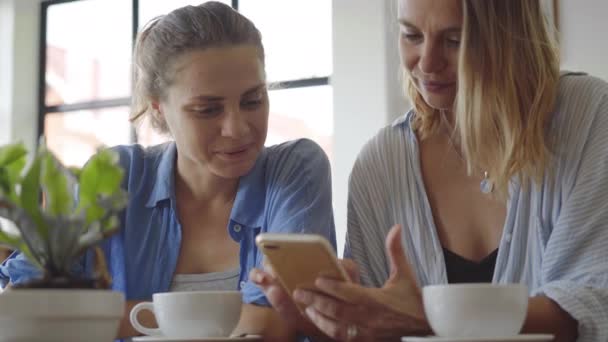 Vrouwen met datum in café. Één delen iets spannend op haar mobiele telefoon — Stockvideo