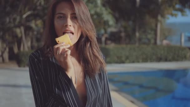 Vrouw likt schijfje ananas — Stockvideo