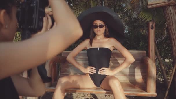 Modelo feminino posa em uma cadeira de praia para fotógrafo feminino — Vídeo de Stock