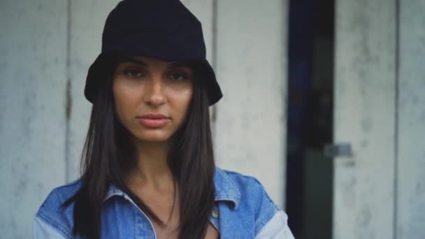 Hermosa mujer morena con sombrero negro mirando a la cámara. calles de la ciudad estilo de vida urbano — Vídeos de Stock