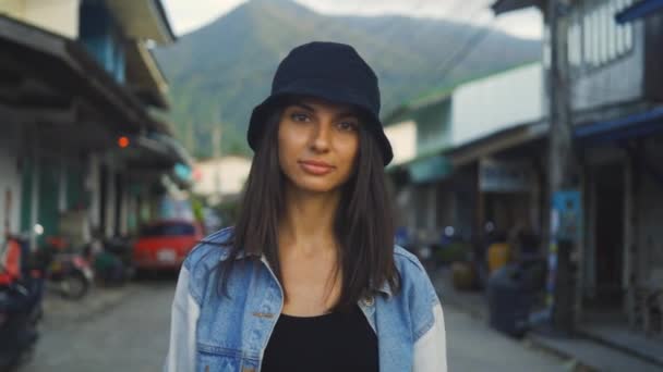Schöne Frau mit schwarzem Hut, die durch die Straßen der Stadt geht und einen glücklichen urbanen Lebensstil lebt — Stockvideo