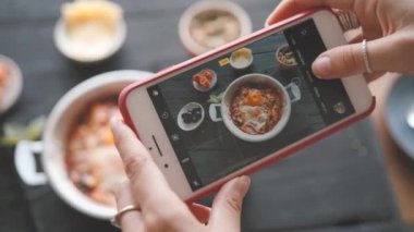 Kadın eli, modern akıllı telefonla yiyeceklerin fotoğrafını çeker. - Yakın çekim. 4K.
