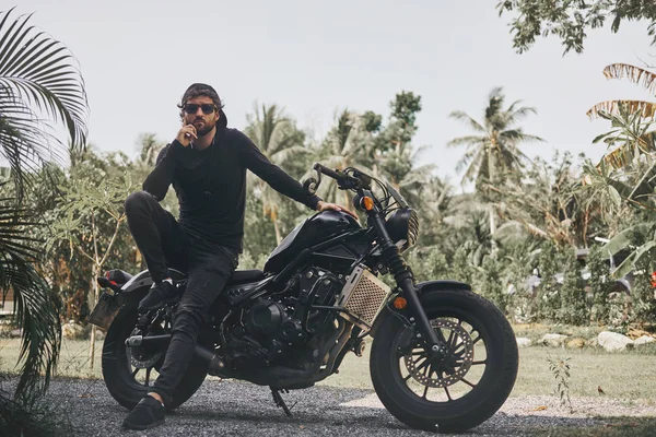 Bonito homem motociclista em desgaste preto sentar-se no estilo clássico moto piloto de café. motocicleta feita sob encomenda — Fotografia de Stock