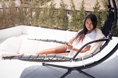 güzel genç Asyalı kadın ile akıllı telefon şezlong üzerinde rahatlatıcı