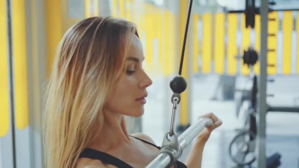 Menina caucasiana jovem atraente em desgaste esportivo trabalhando com equipamento de fitness em um ginásio profissional — Vídeo de Stock
