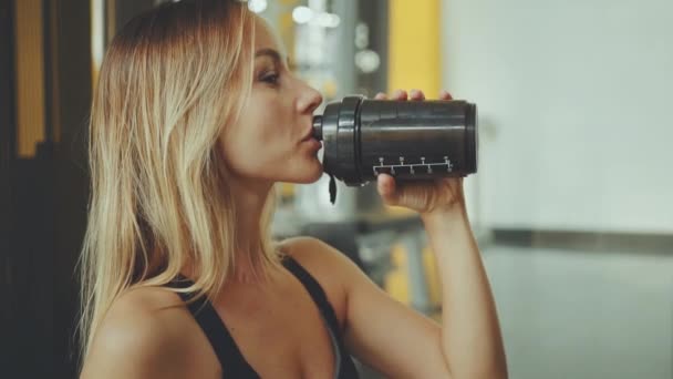 Atractivo joven deporte chica beber agua en un gimnasio profesional — Vídeo de stock