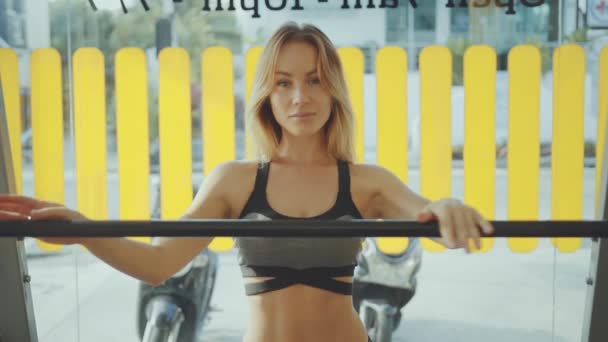 Piękna młoda kobieta w odzieży sportowej stojącej w siłowni i patrząc na kamerę — Wideo stockowe