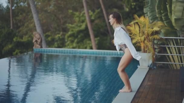 Красива молода жінка з сексуальним тілом у купальнику стрибає в басейн — стокове відео