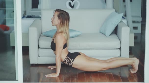 Tijd voor yoga. Aantrekkelijke jonge vrouw trainen tijdens het rusten thuis — Stockvideo