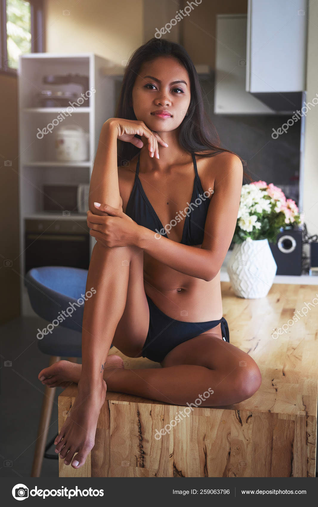 Sexy Asian girl sitting on the table and relax in kitchen at home Stock  Photo by ©romablack 259063796