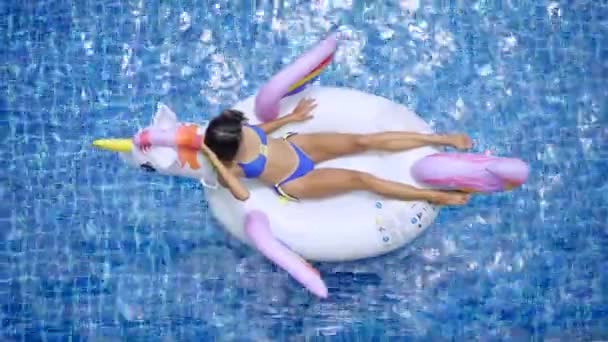 Sexy asian woman in bikini relaxing on the unicorn in a swimming pool — Stock Video