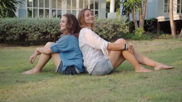 Счастливая лесбийская пара сидит спиной друг к другу — стоковое видео