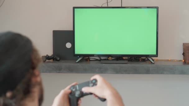 Homem joga com um controlador de jogo whiile situado no sofá em casa — Vídeo de Stock