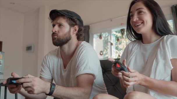 Ember és nő játszik videojátékokkal, és ül a kanapén — Stock videók