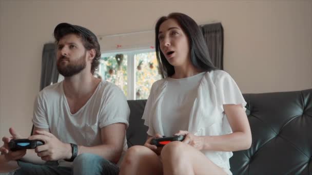 男子庆祝，而玩视频游戏与女人坐在沙发上 — 图库视频影像