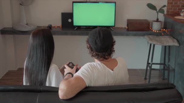 Férfi és nő ül a kanapén játszik videojátékokkal a zöld képernyő — Stock videók
