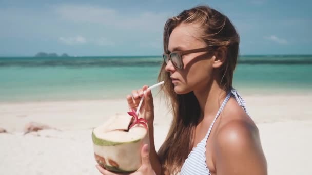 Vrouw drinken verse kokoswater met stro op het strand — Stockvideo