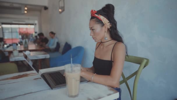 Vrouw die op haar laptop in een café werkt — Stockvideo