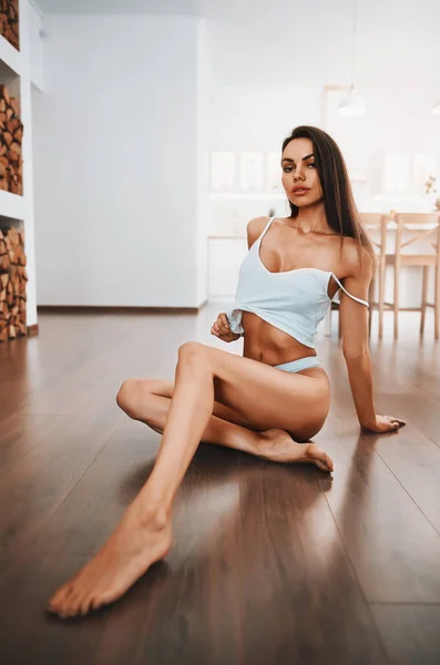 Sexy meisje in lingerie zitten op een vloer in een keuken — Stockfoto