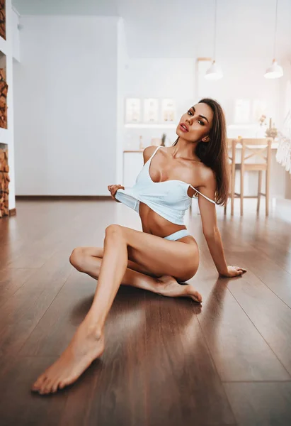 Sexy girl in lingerie sitting on a floor in a kitchen — Stock Photo, Image
