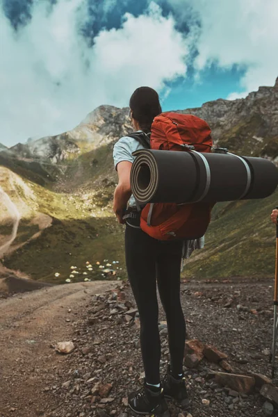 Turista s červeným batohem stojí na vrcholu hory a těší kempování údolí pohled — Stock fotografie