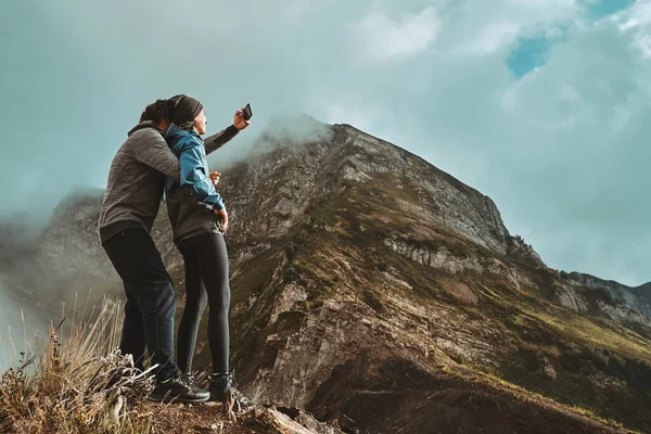 Mladý pár objetí na útesu a pořídí selfi fotografii — Stock fotografie