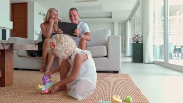 Χαριτωμένο μικρό παιδί κάθεται στο πάτωμα και παίζει με πολύχρωμα παιχνίδια κατασκευής — Αρχείο Βίντεο