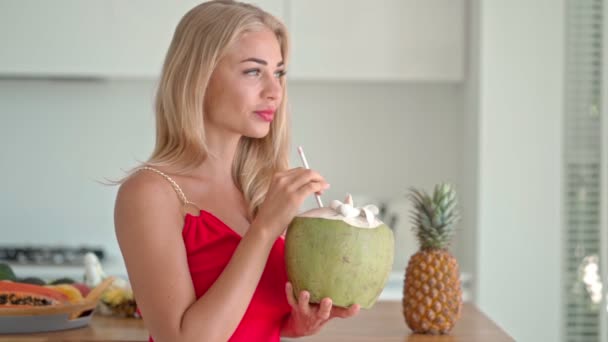 Šťastná mladá žena v kuchyni s kokosem v ruce — Stock video