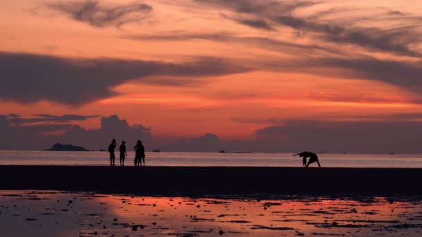 Gente caminando por la playa al atardecer — Vídeos de Stock
